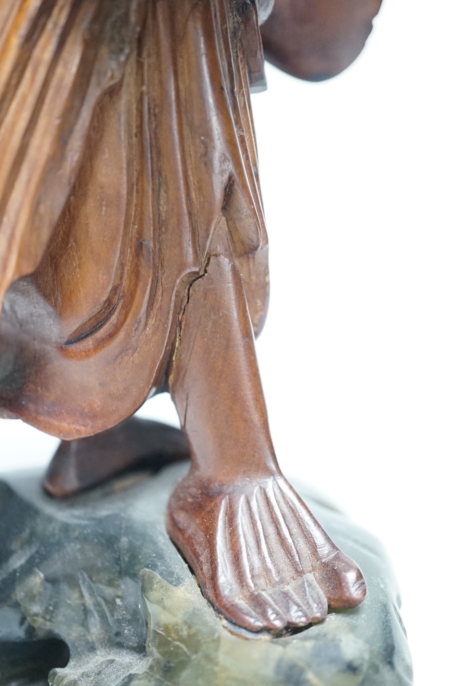 An early 20th century Chinese hardwood carving of a luohan, on soapstone base, 36cm tall
